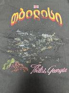 Dark charcoal graphic T-shirt close-up of logo and 'Tbilisi, Georgia' text