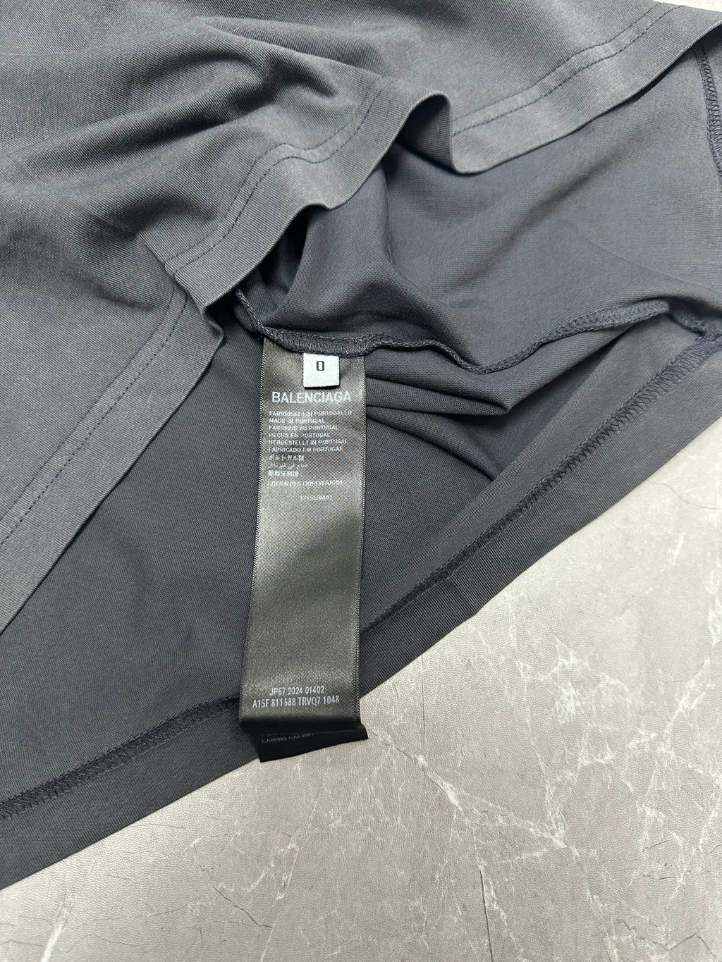 Dark gray T-shirt close-up showing neckline seam and BALENCIAGA size tag