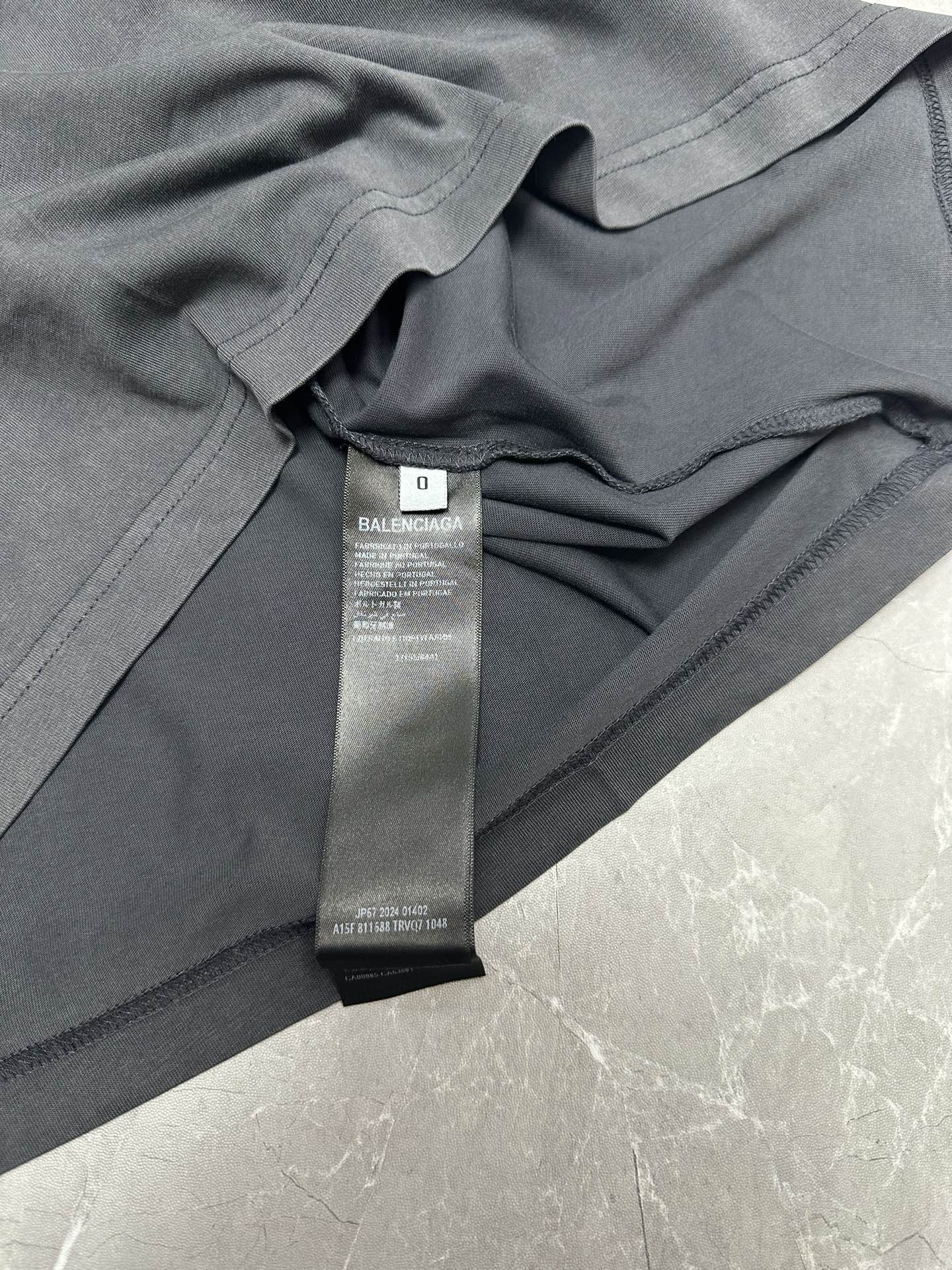 Dark gray T-shirt close-up showing neckline seam and BALENCIAGA size tag