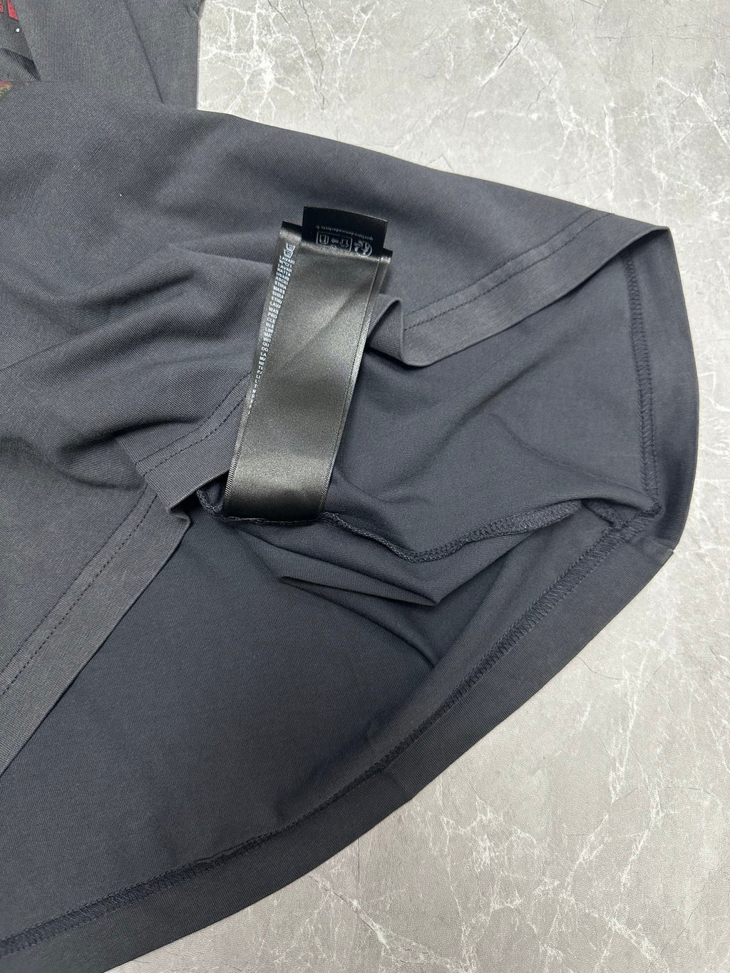 Dark gray T-shirt sleeve and hem close-up with black hang tag