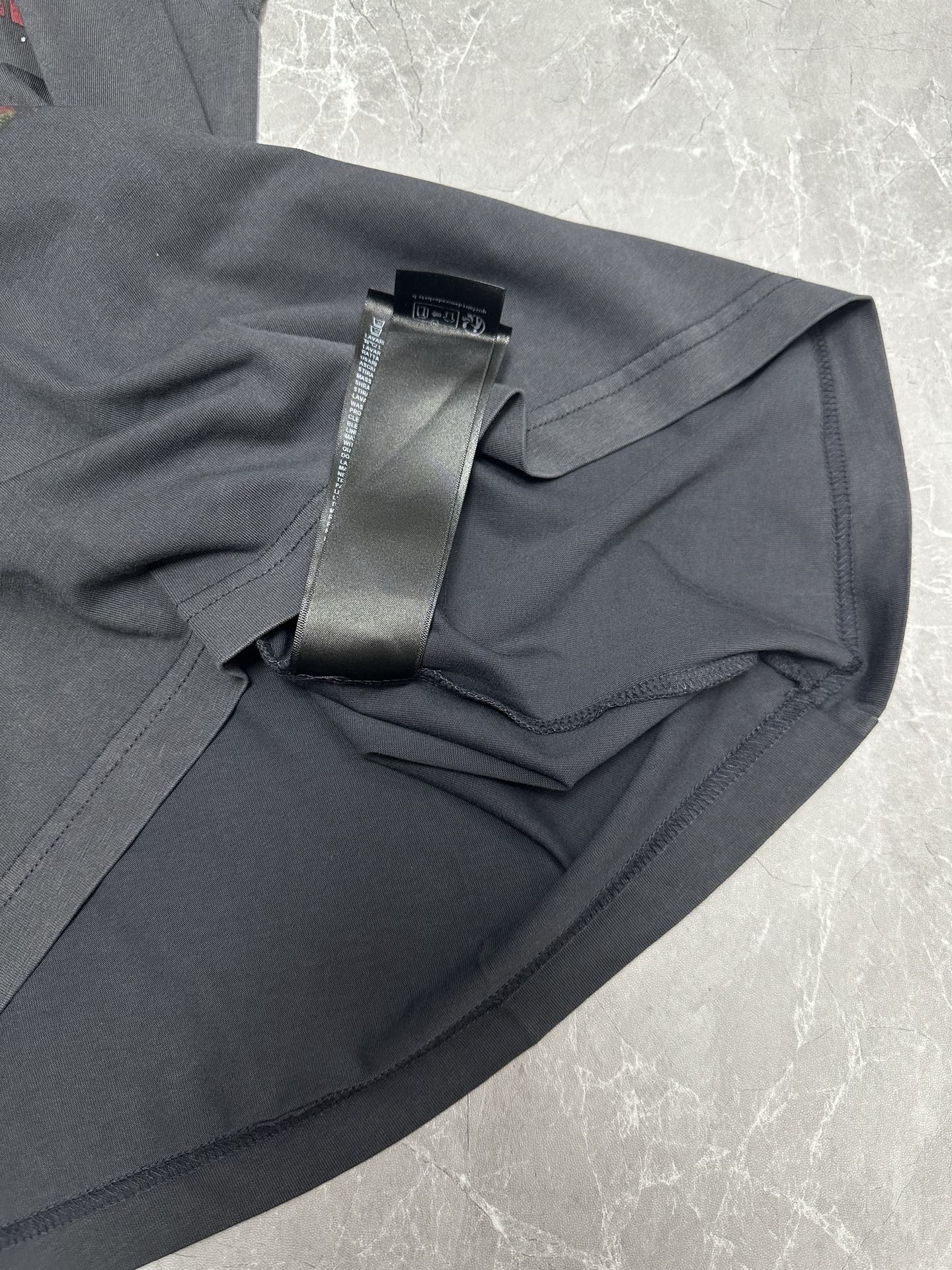 Dark gray T-shirt sleeve and hem close-up with black hang tag