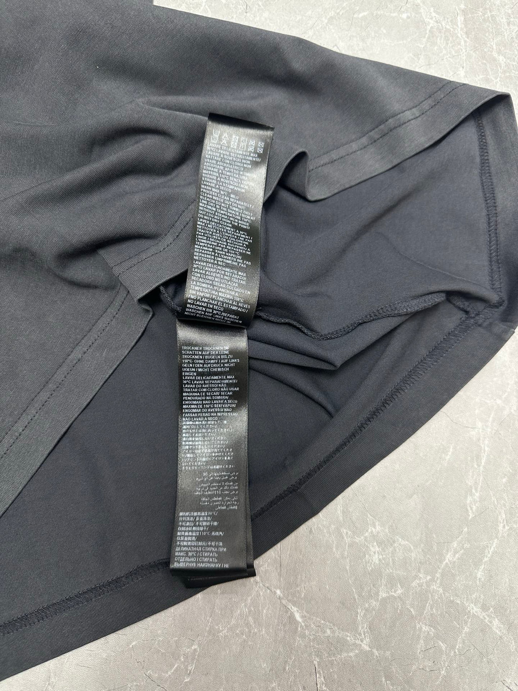 Dark gray T-shirt close-up of side tag loop and printed care label