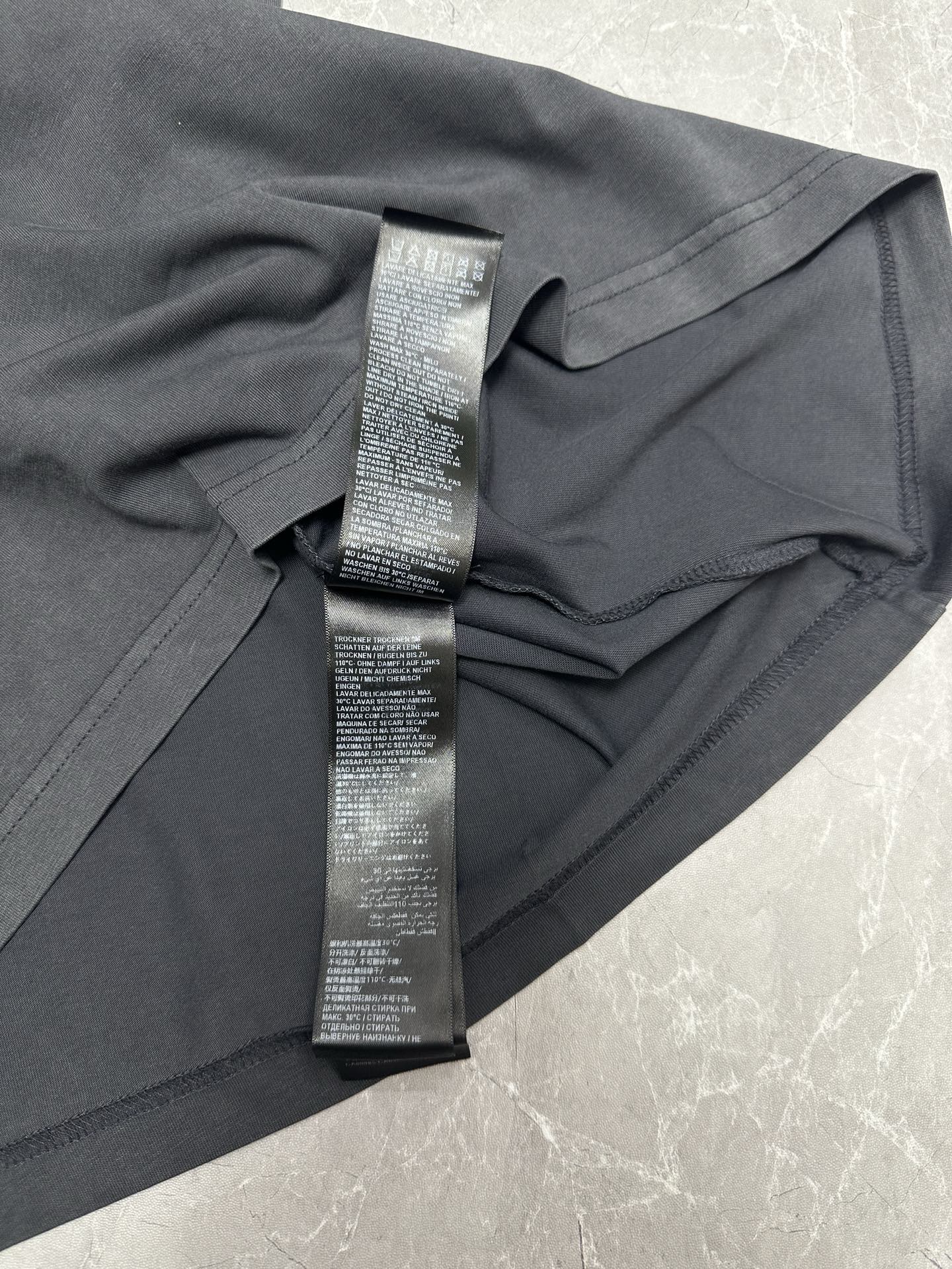 Dark gray T-shirt close-up of side tag loop and printed care label