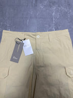 Cream waistband of cargo shorts with button closure and belt loops.