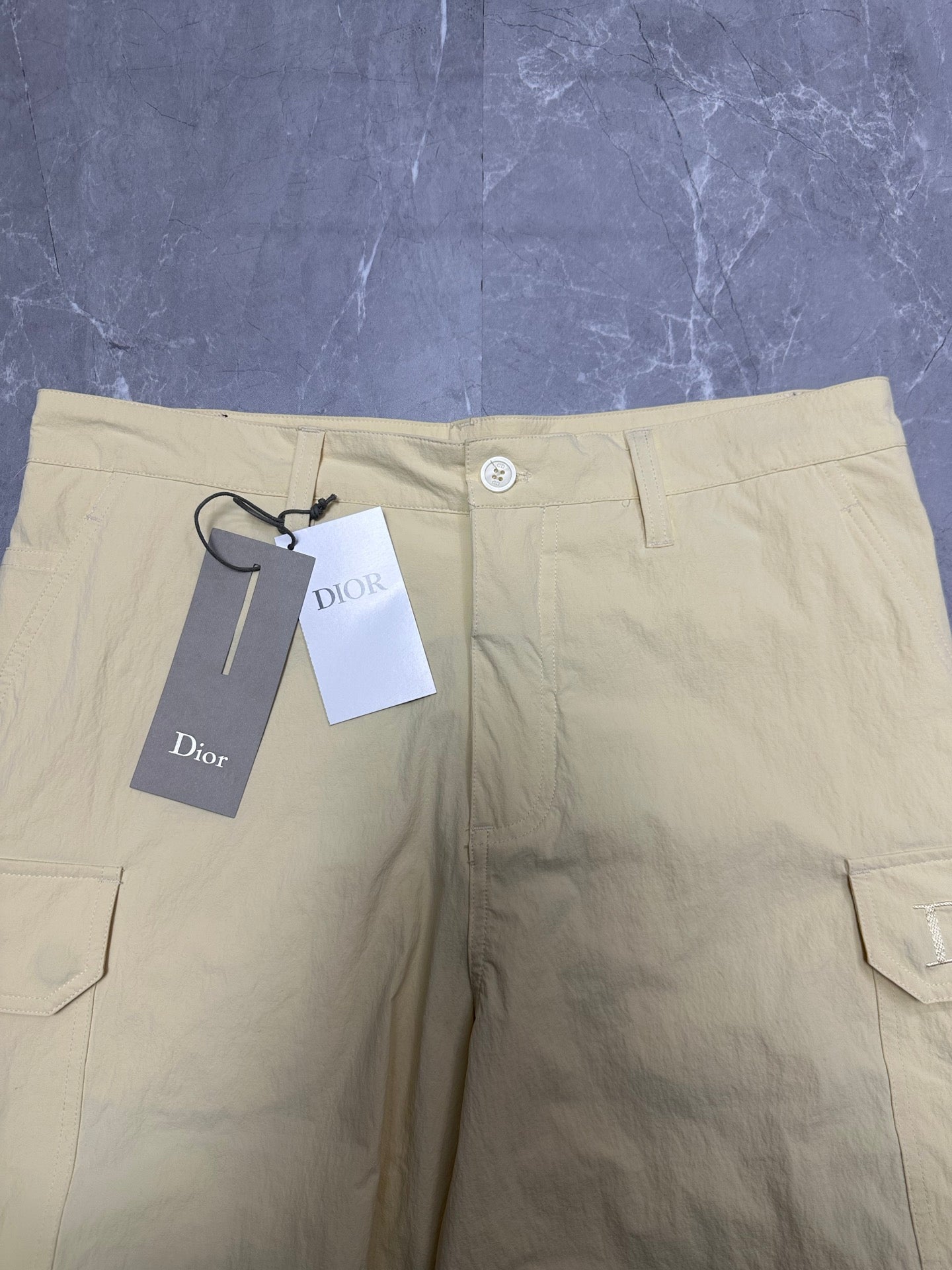 Cream waistband of cargo shorts with button closure and belt loops.