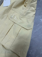 Cream cargo shorts with side pocket and embroidered logo detail at hem.