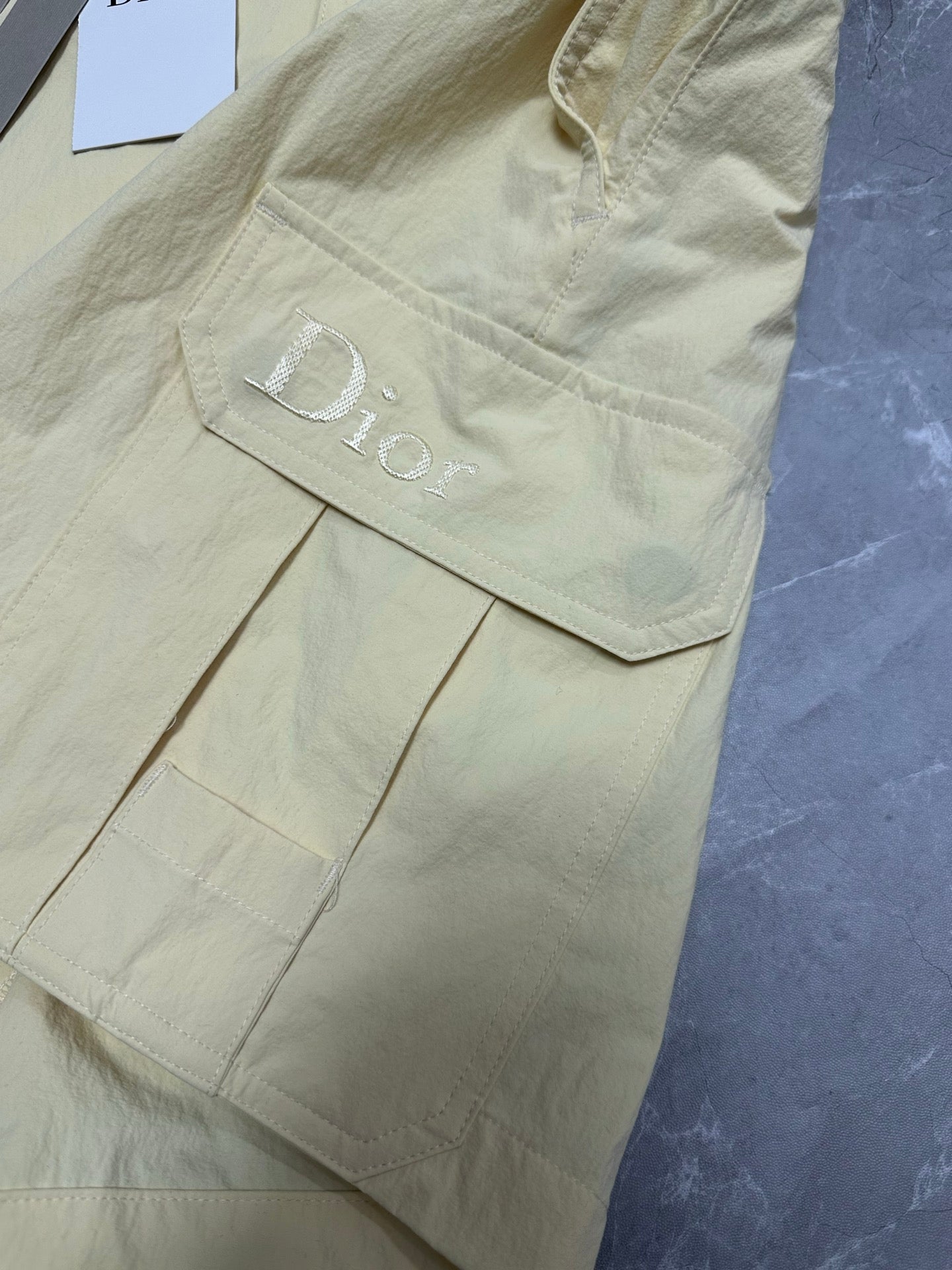 Cream cargo shorts with side pocket and embroidered logo detail at hem.