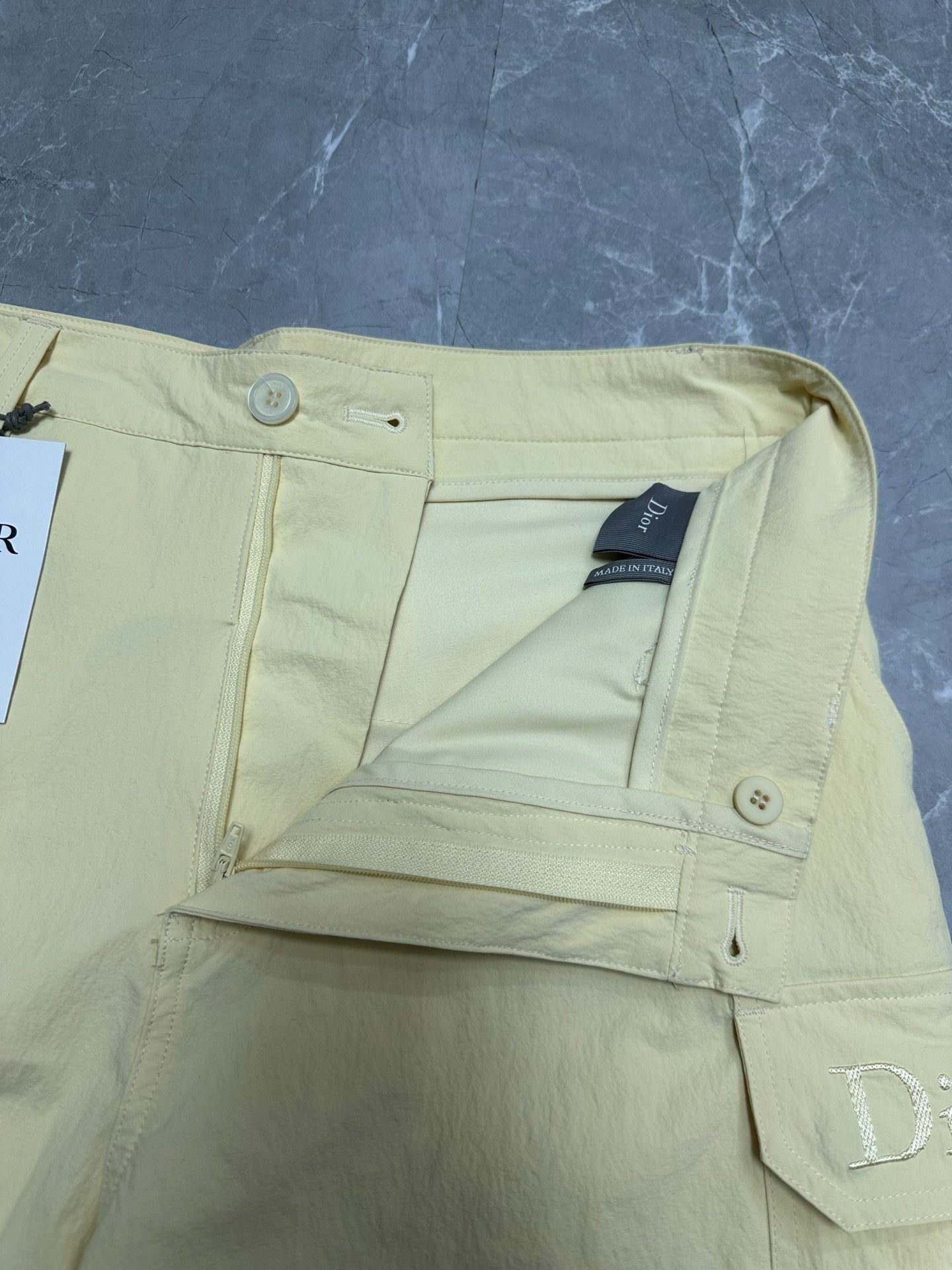 Cream cargo shorts with button closure and inner waistband label.