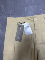 Cream cargo shorts front with button closure, belt loops, and attached tags.