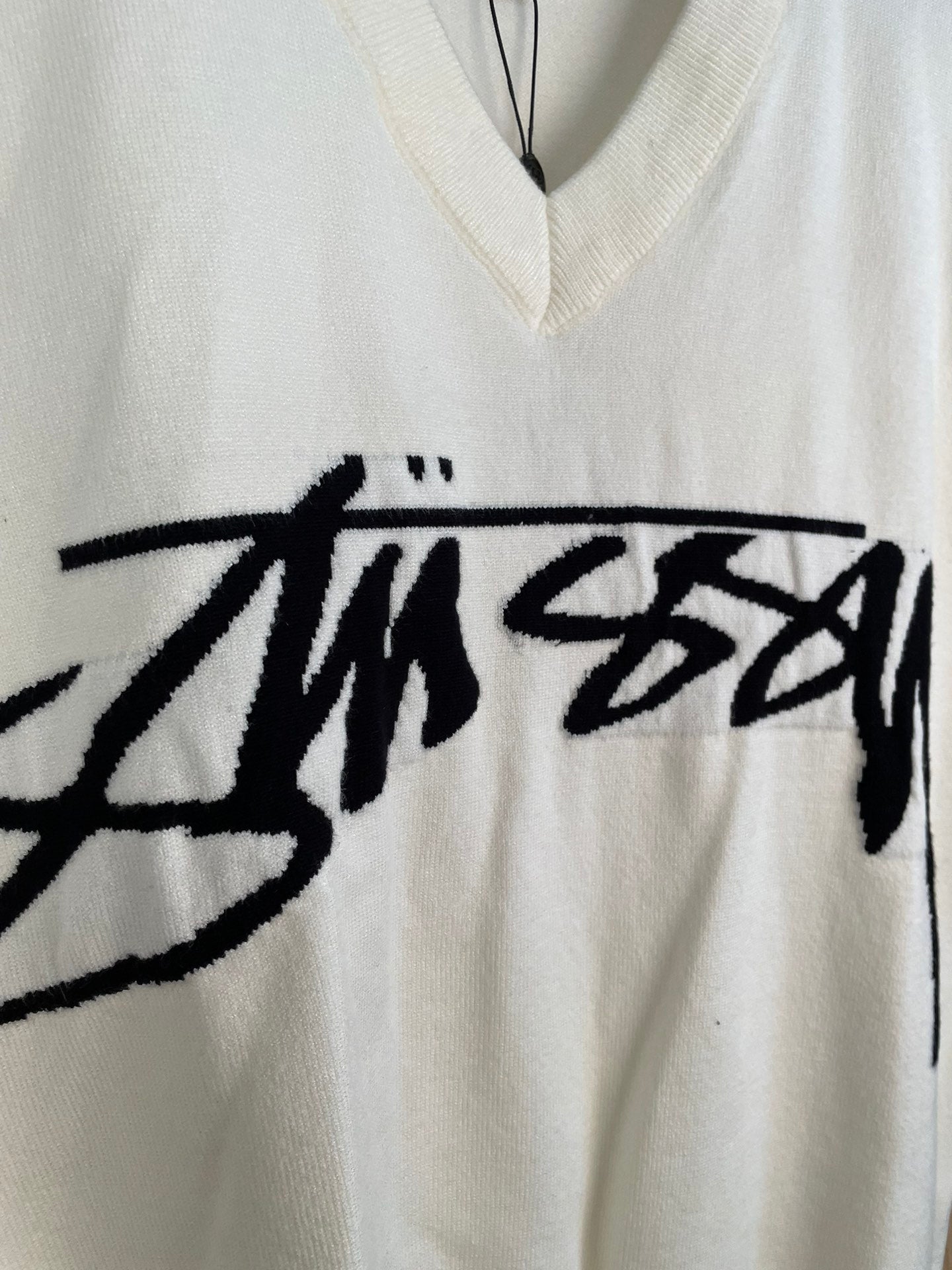 White sleeveless knit vest front with large black Stussy graphic print