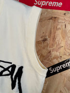 White sleeveless knit vest armhole and side seam with partial black Stussy graphic