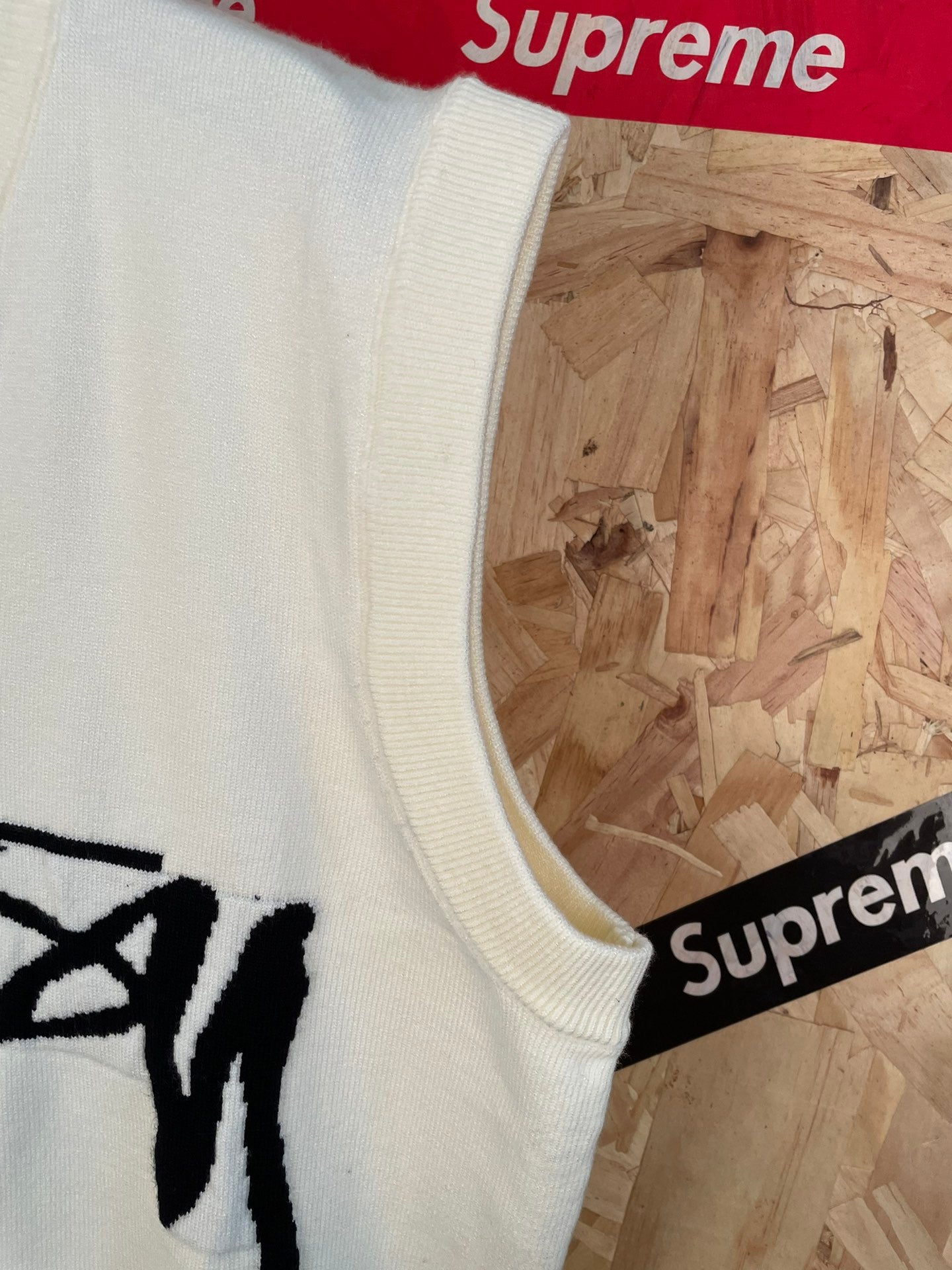 White sleeveless knit vest armhole and side seam with partial black Stussy graphic