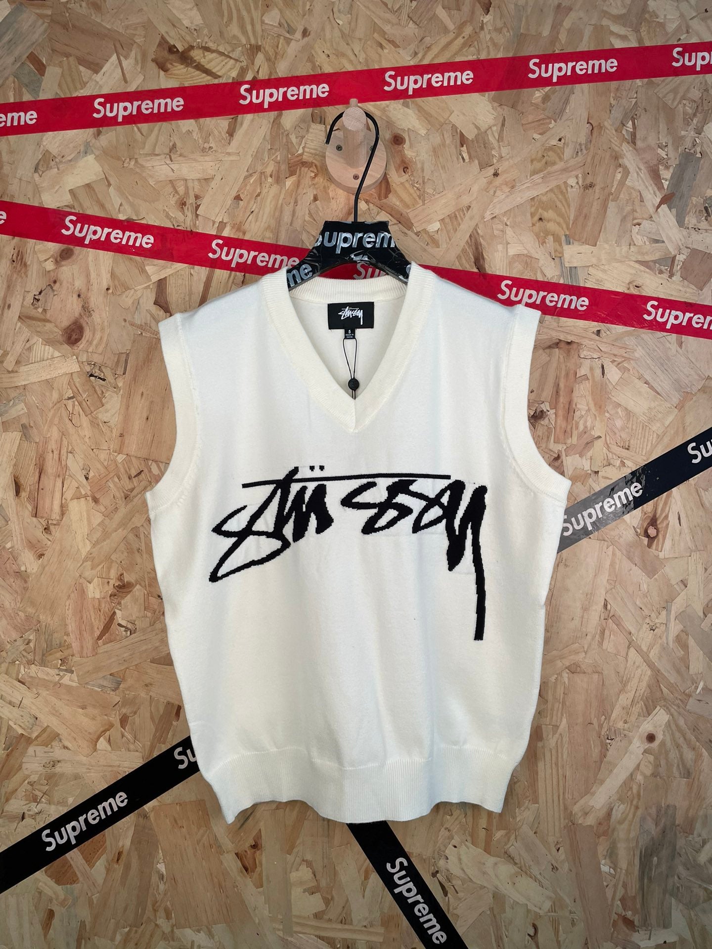 White sleeveless knit vest with V-neck and black Stussy logo graphic on front