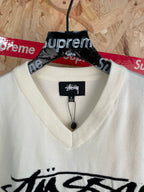 White sleeveless knit vest with V-neck and black Stussy logo graphic, close-up