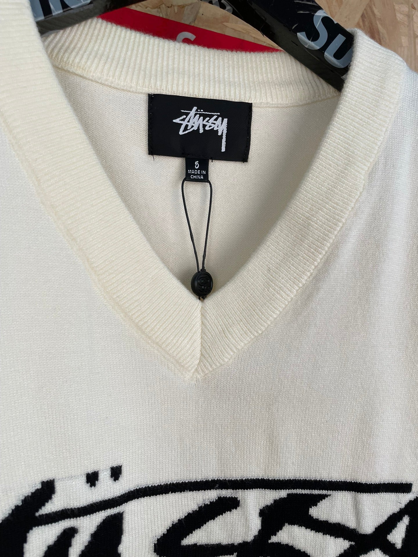 White sleeveless knit vest neckline with V-neck rib trim and Stussy label