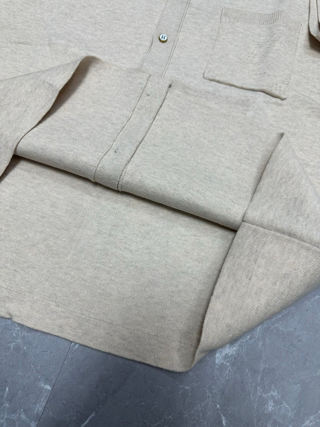 Light beige polo shirt front placket and chest pocket, button details