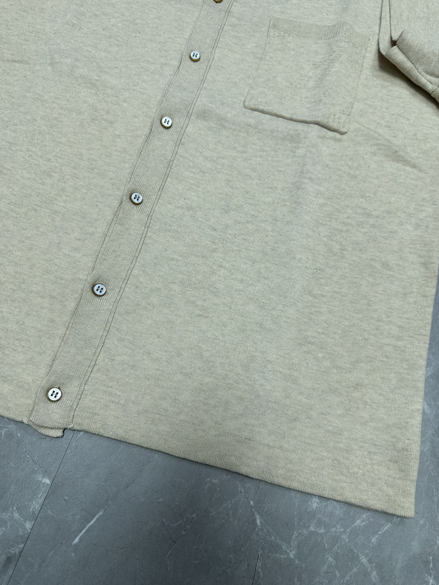 Light beige polo shirt hem and button front, chest pocket panel visible