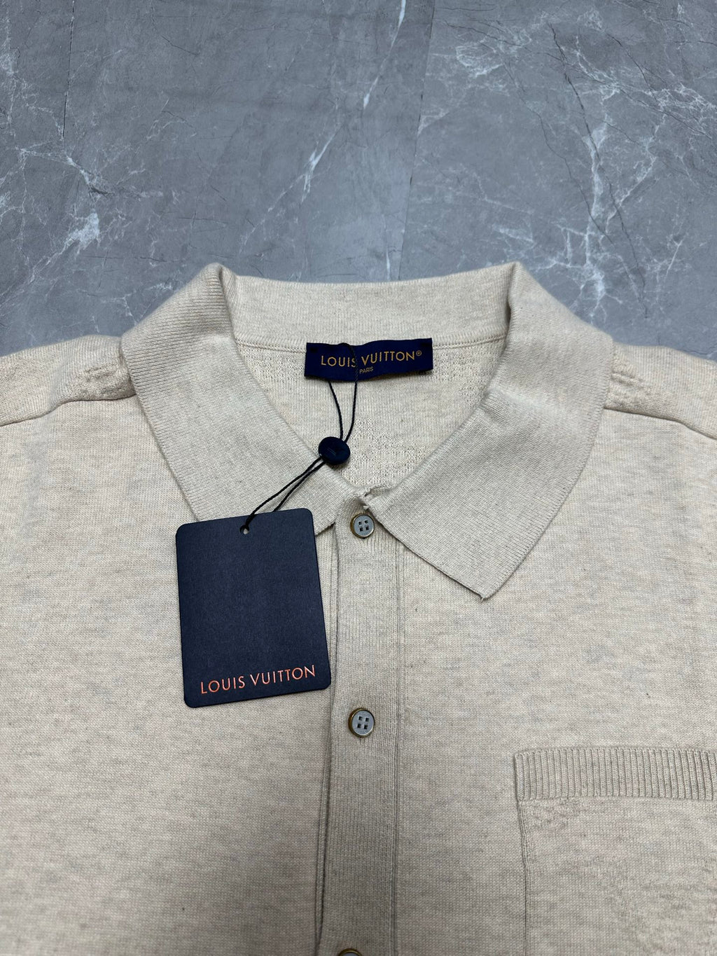 Light beige polo shirt with pointed collar and button placket, with neck tag