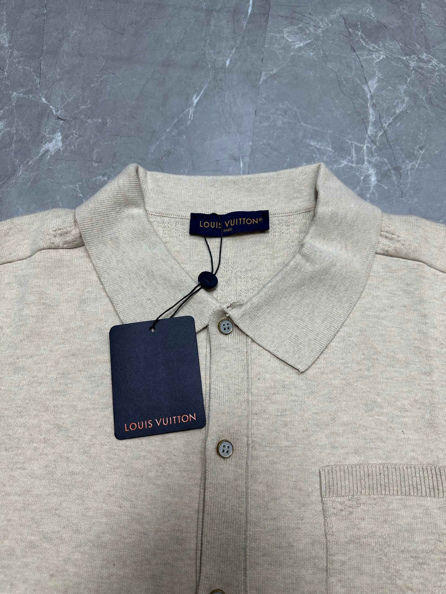 Light beige polo shirt with pointed collar and button placket, with neck tag