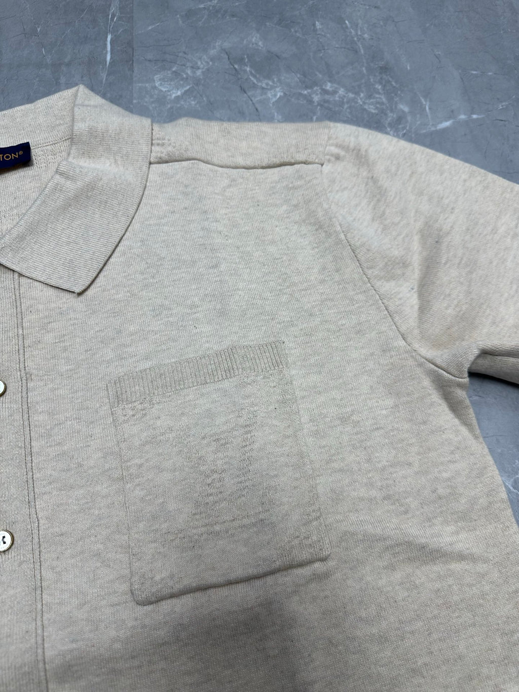 Light beige polo shirt fabric detail, ribbed pocket panel and button placket