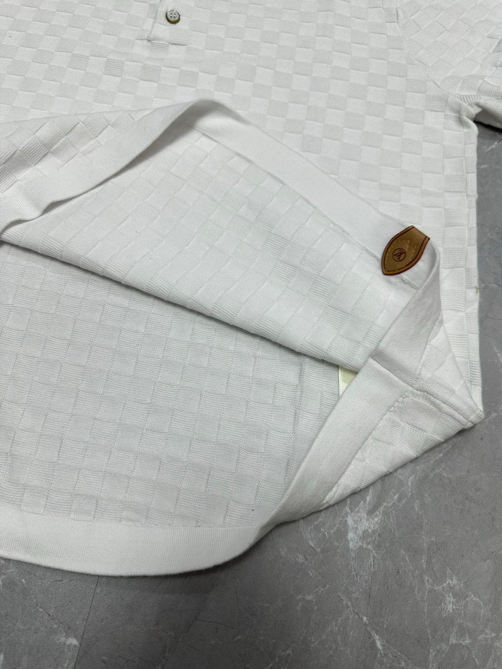 Louis Vuitton white polo shirt folded with collar, sleeve, and textured checker knit