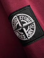 Stone Island embroidered logo patch on maroon sweatshirt sleeve