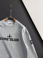 Grey crewneck sweatshirt with Stone Island chest logo and sleeve patch