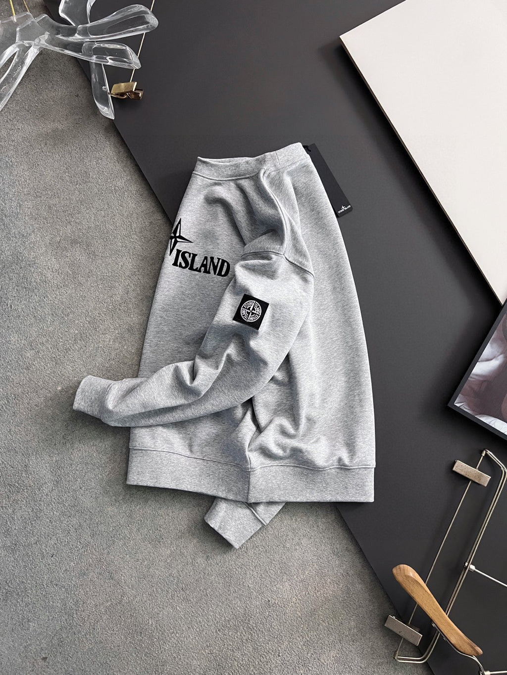 Grey sweatshirt laid flat with Stone Island chest logo and sleeve patch