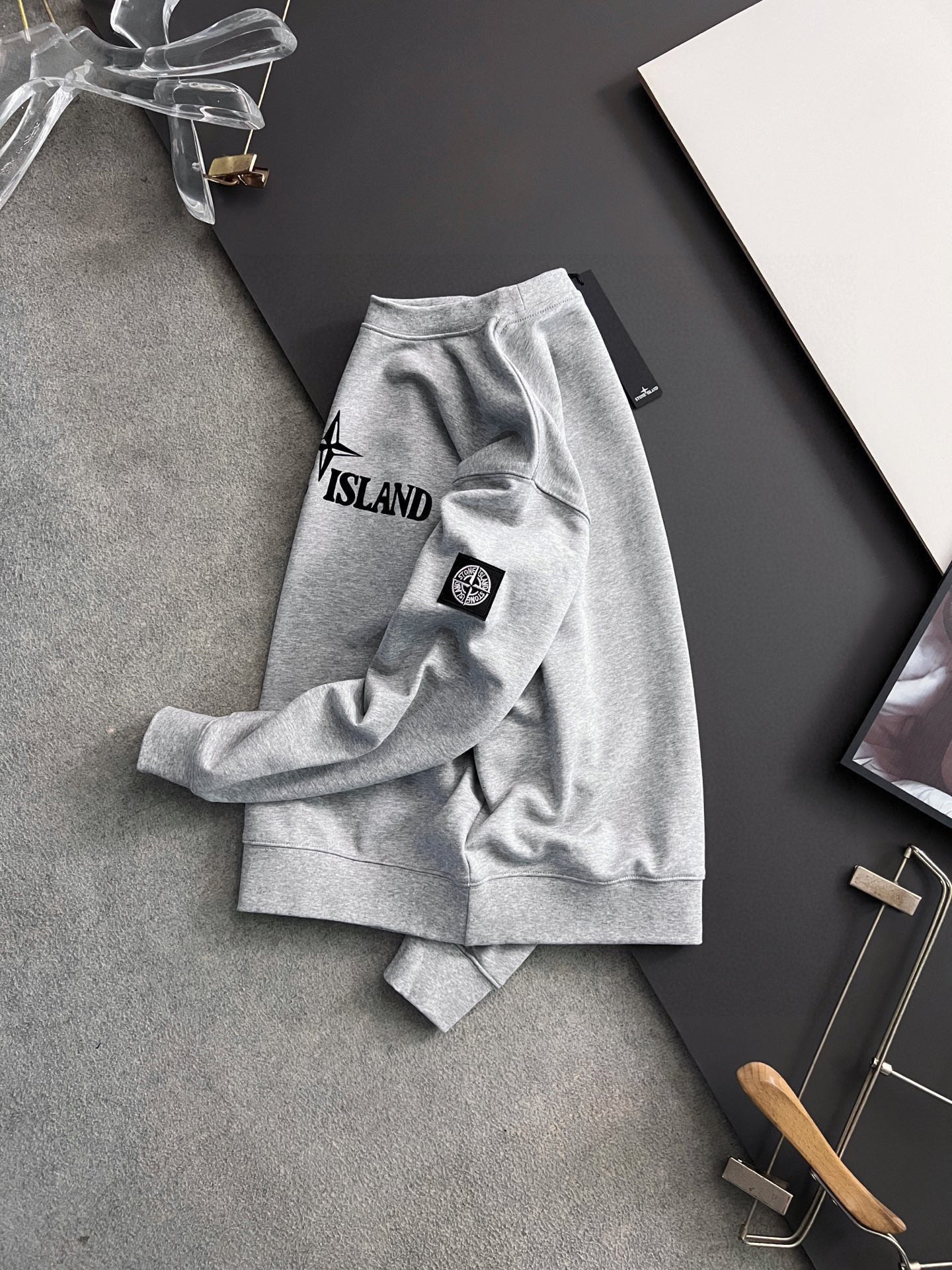 Grey sweatshirt laid flat with Stone Island chest logo and sleeve patch