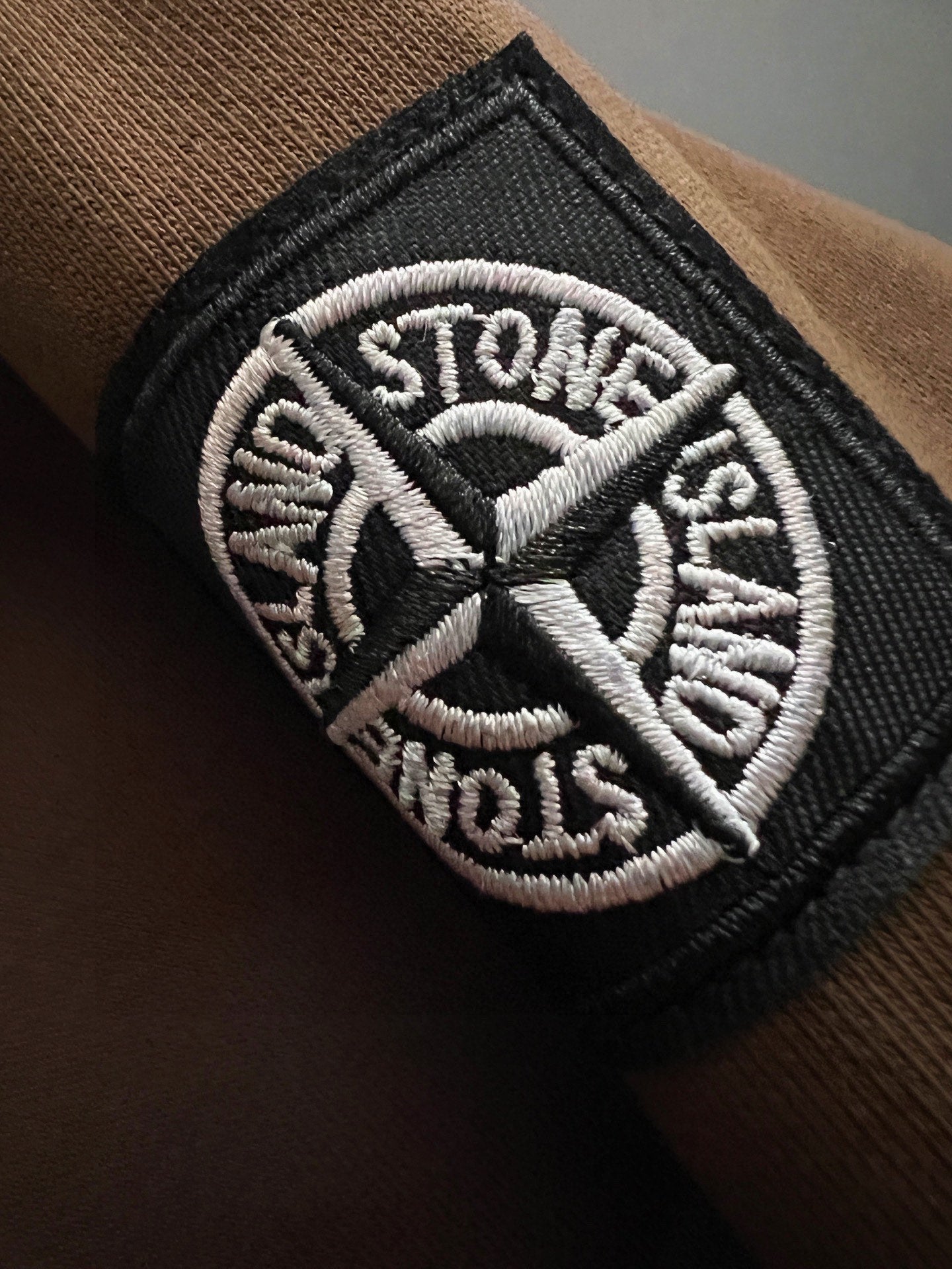 Embroidered Stone Island logo patch on dark sleeve cuff