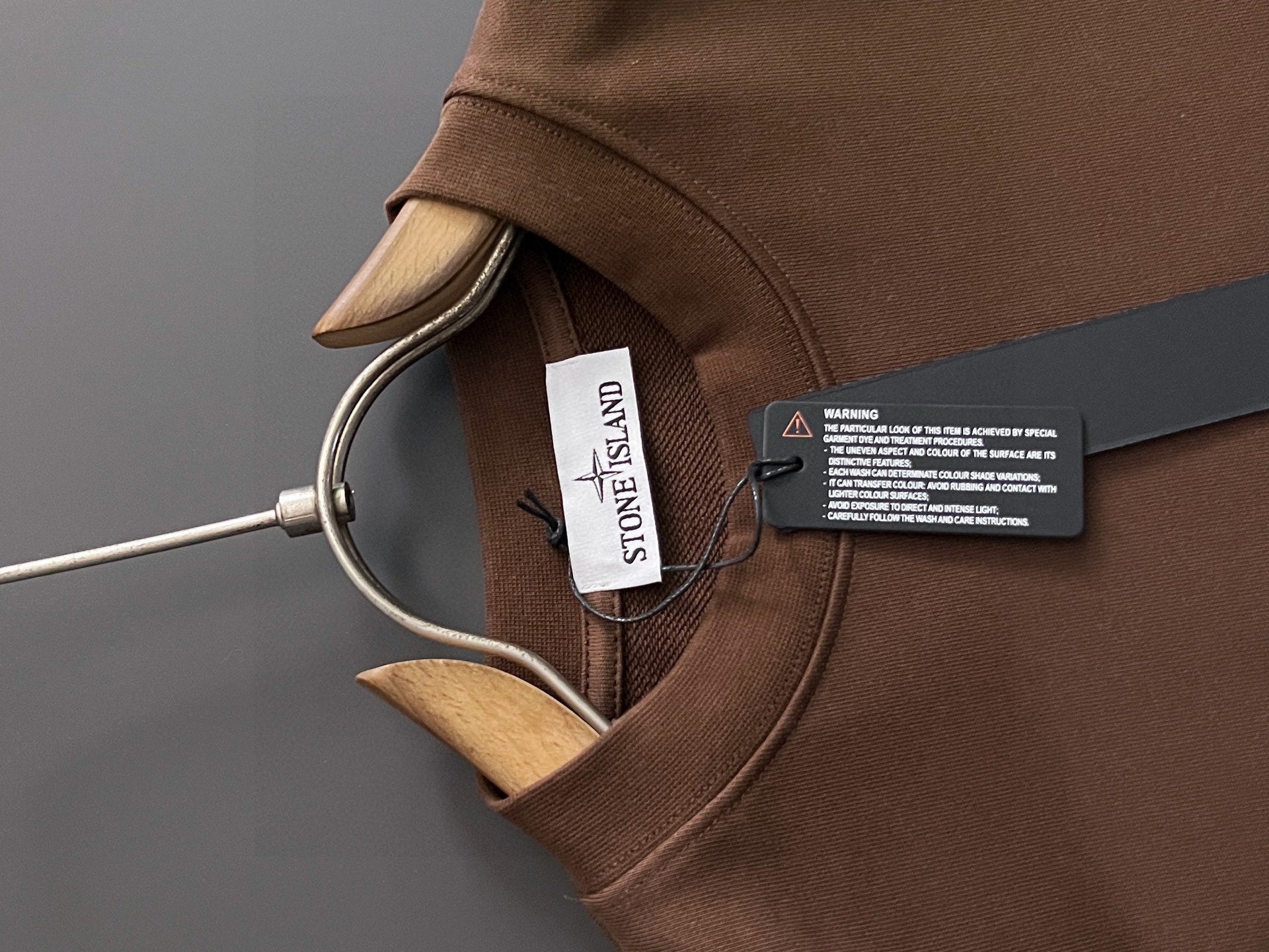 Brown crewneck sweatshirt collar with Stone Island label and neck tag