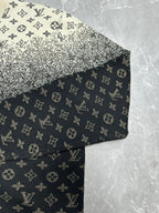 Sleeve and hem of monogram sweater with beige speckled texture over dark knit