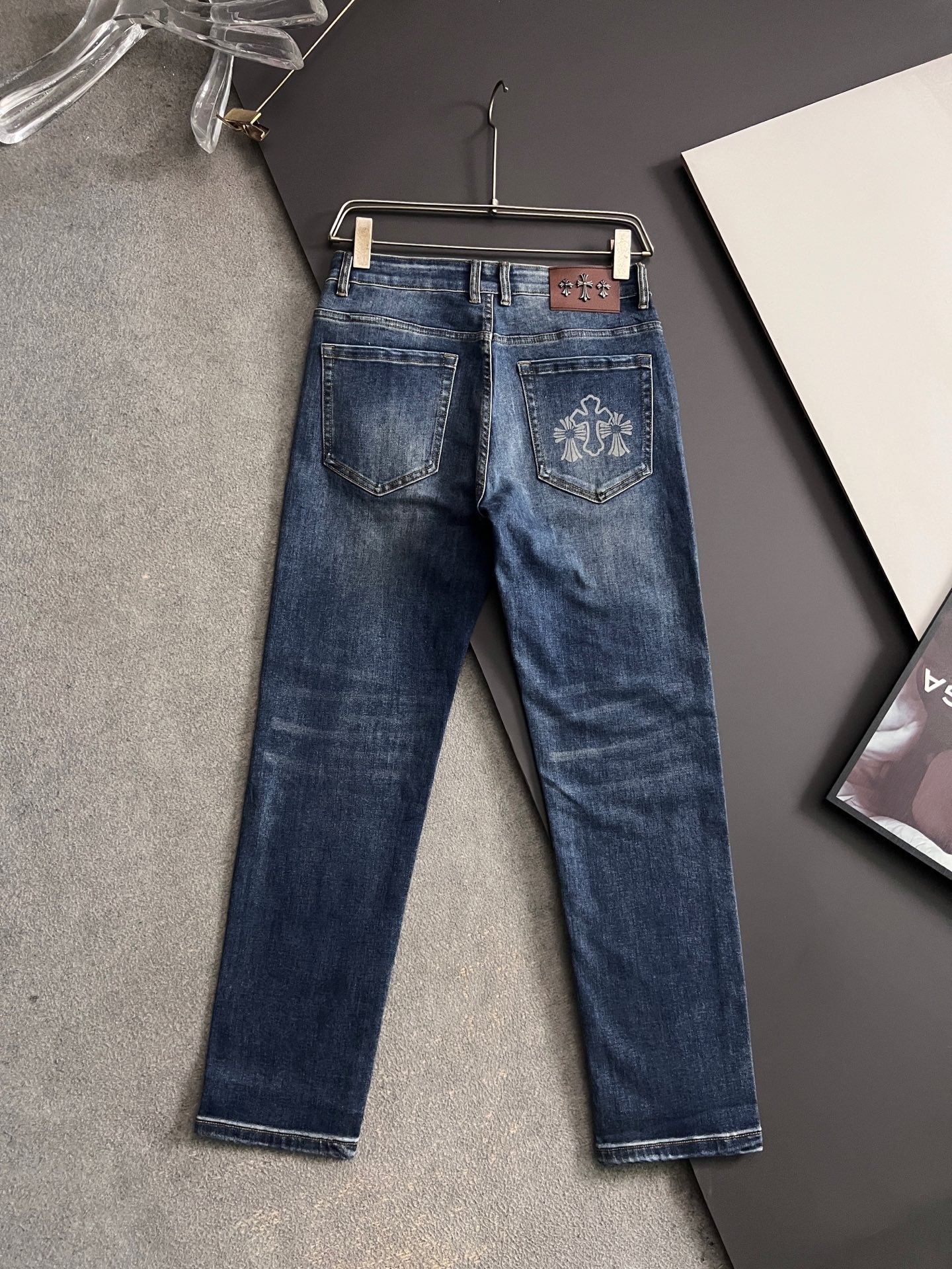 Blue denim pants with back pockets and embroidered decorative emblem