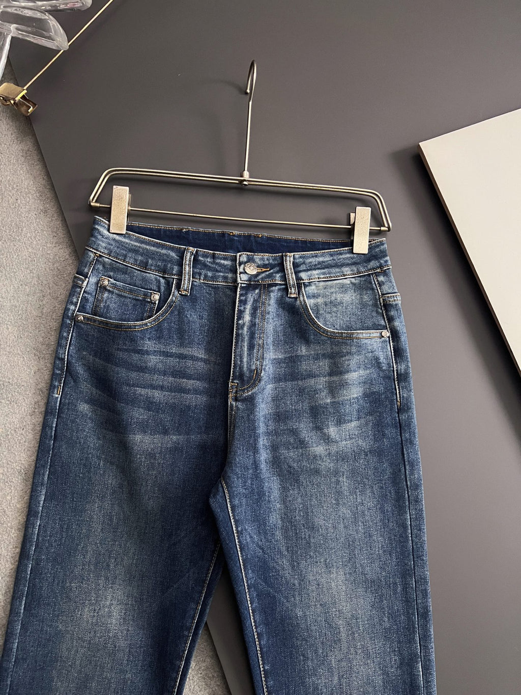 Blue denim pants with belt loops, button fly, and stitched waistband
