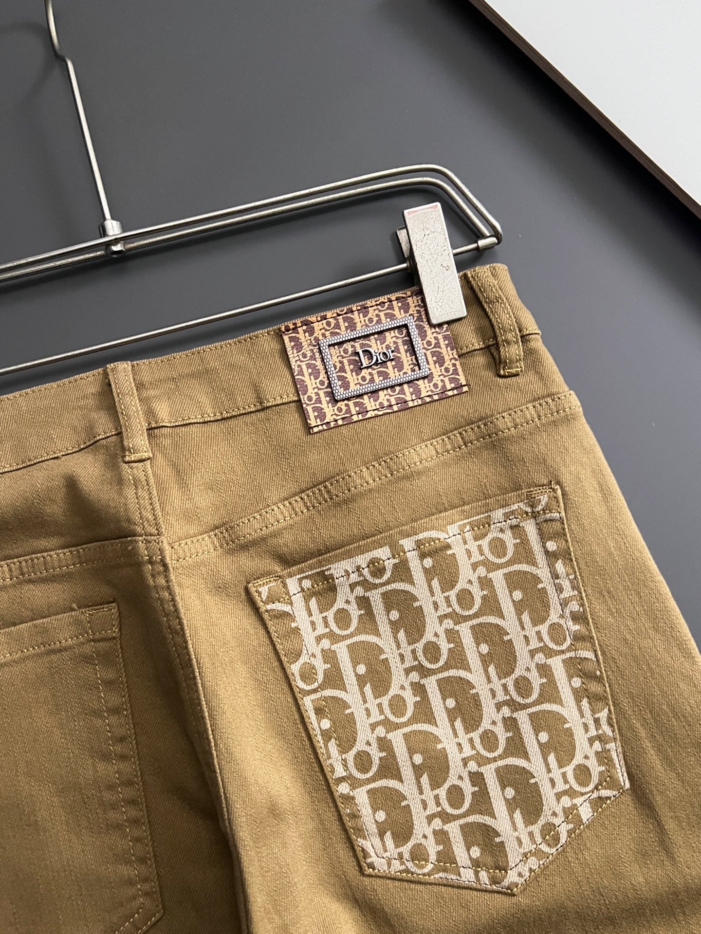 Olive Dior jeans close-up, front logo pocket patch and waistband button