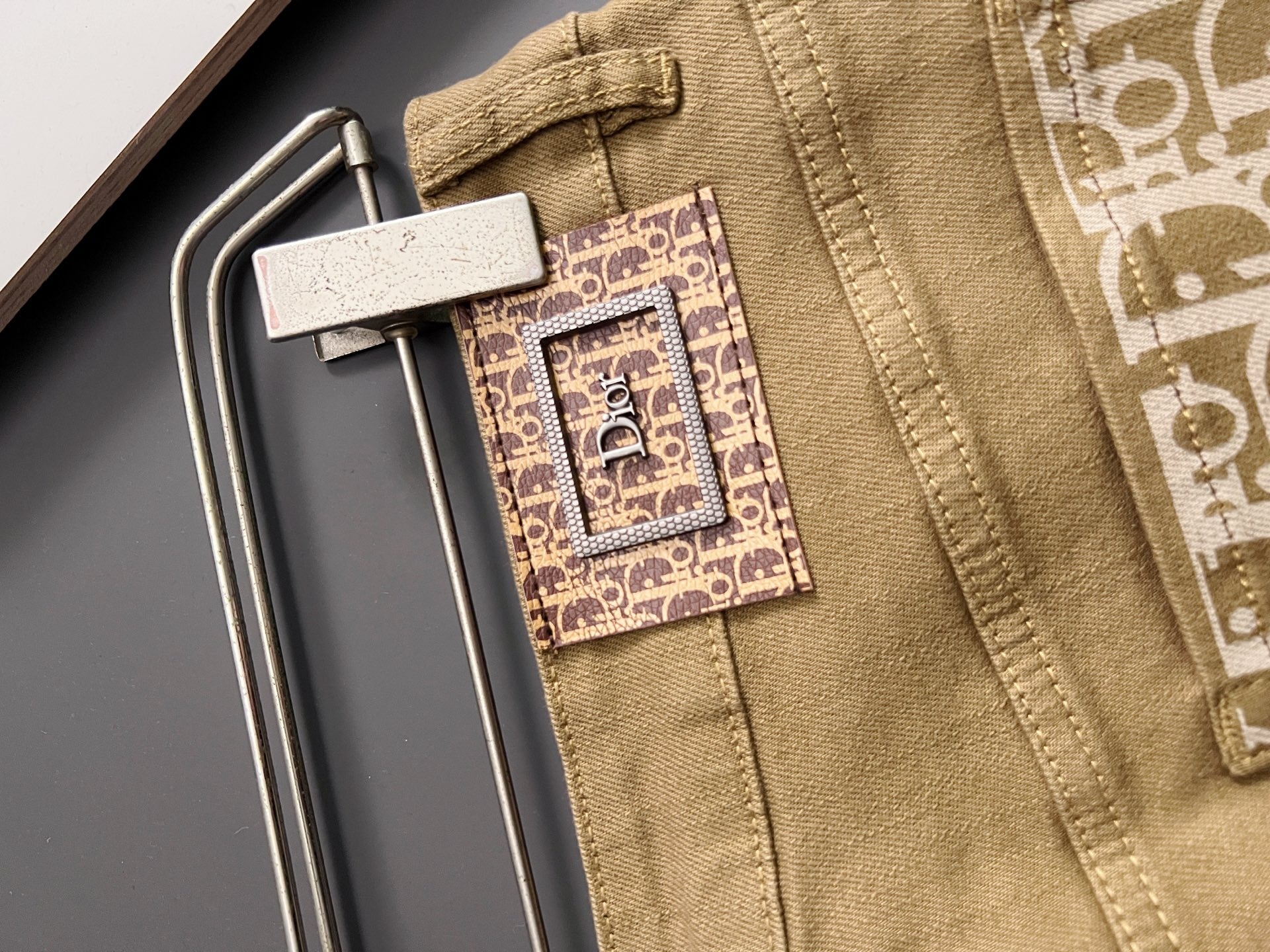 Olive Dior jeans close-up, waistband label and decorative logo patch