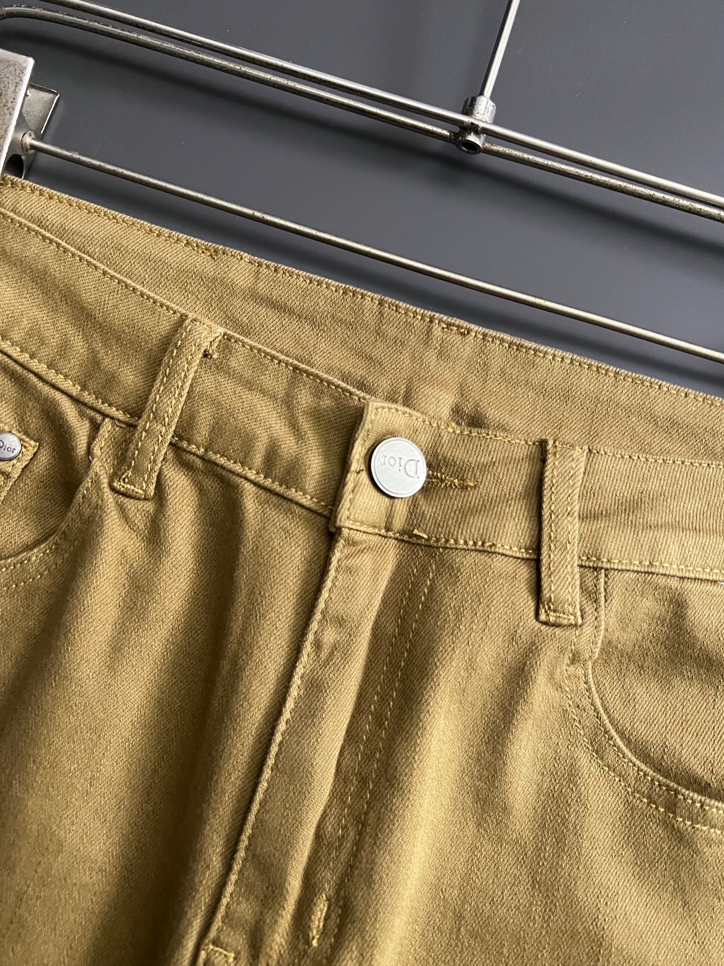 Olive Dior jeans close-up, front pocket with button and belt loops