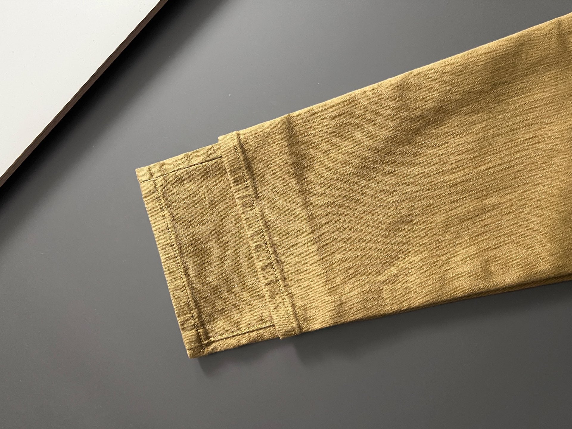 Olive Dior jeans hem close-up with stitched cuff