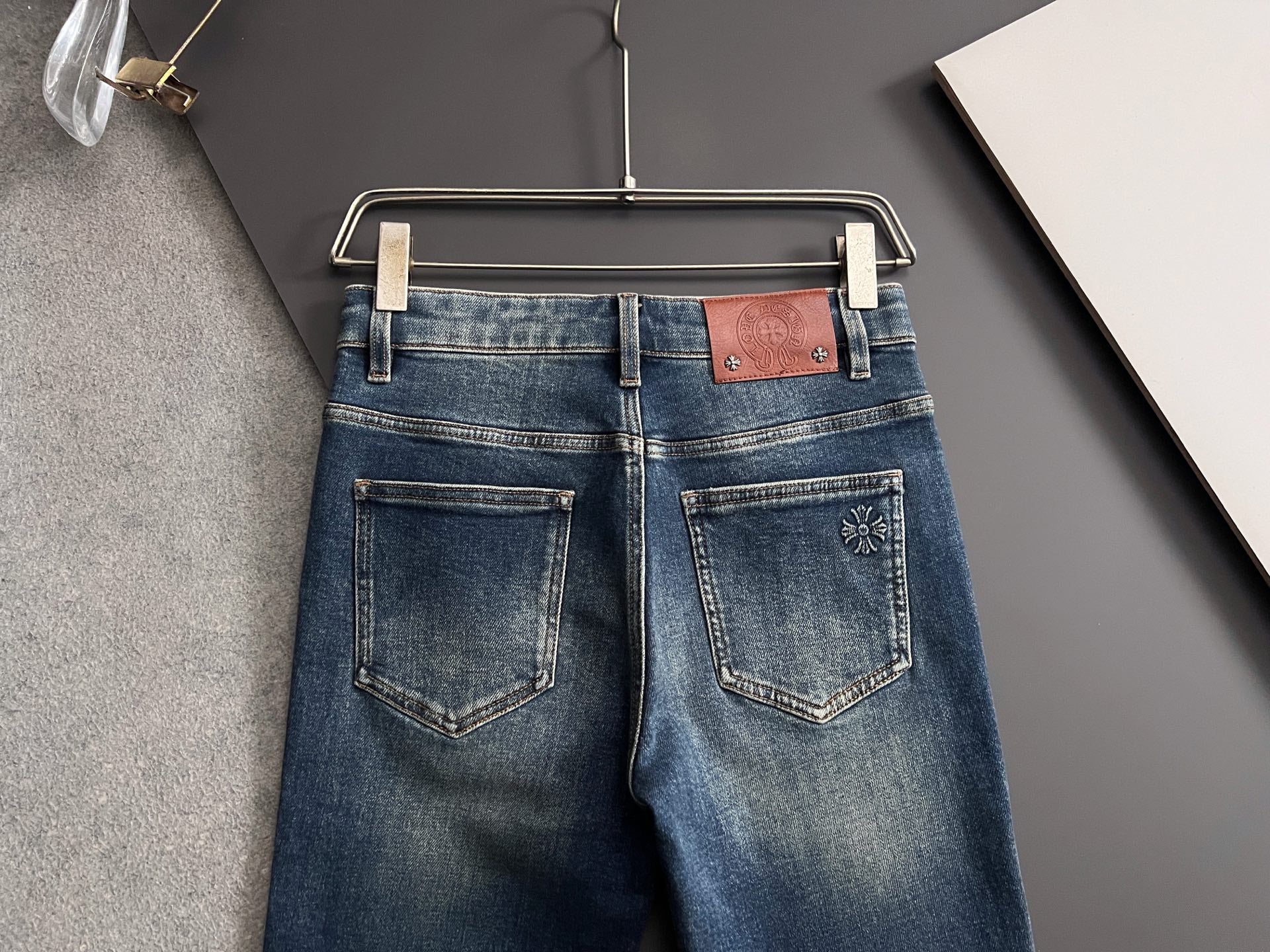Blue denim jeans on hanger, front view with patch-style pocket details