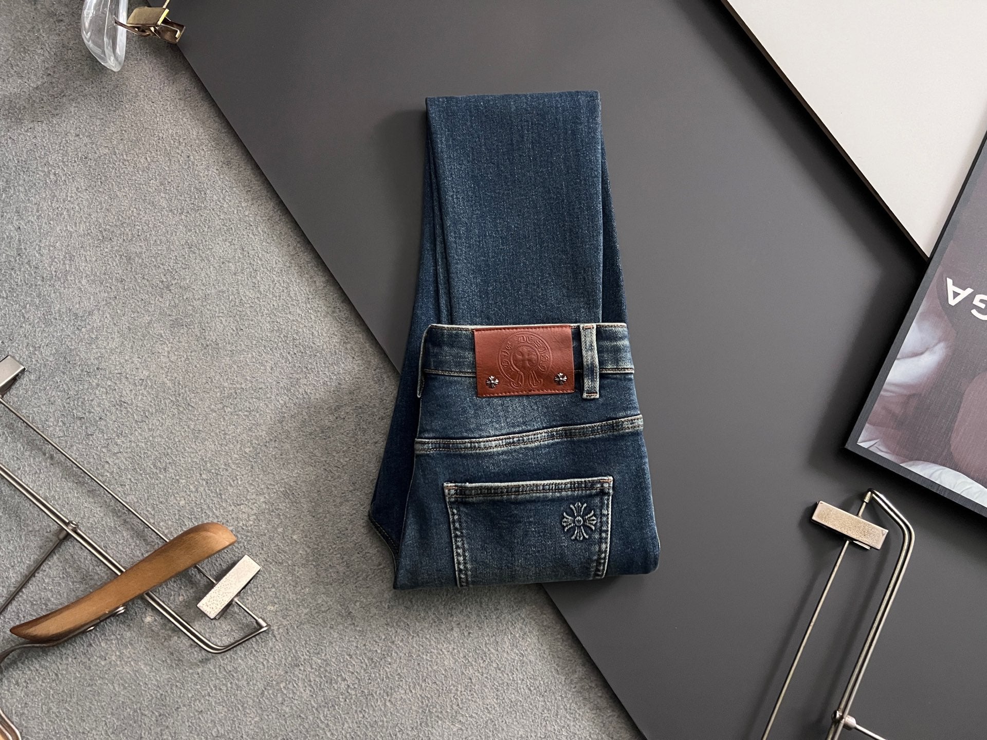 Folded blue denim jeans with brown leather-look patch waistband