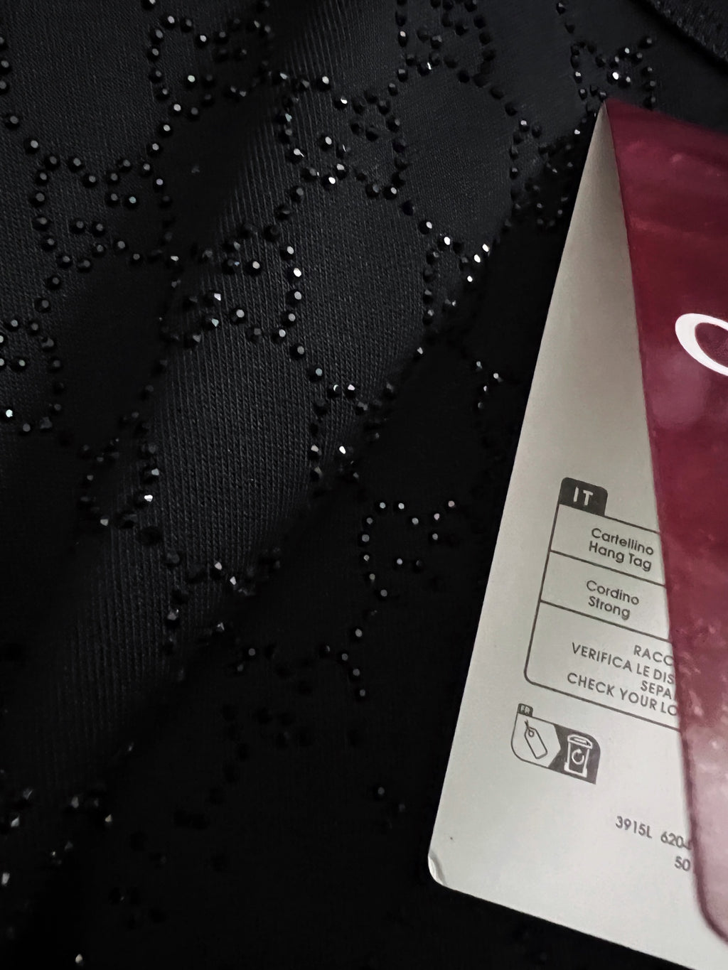 Black Gucci top fabric close-up with dotted patterned texture and product tag