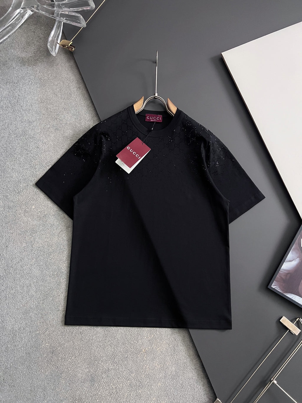 Black Gucci short-sleeve top on hanger with small front buttons and subtle print