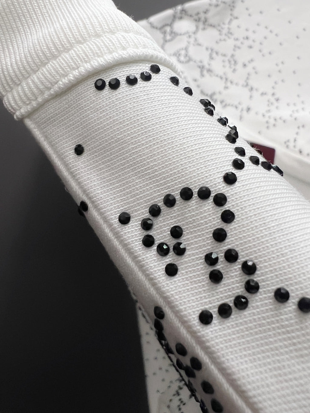 Gucci sleeve detail with black stud-like embellishments on white knit