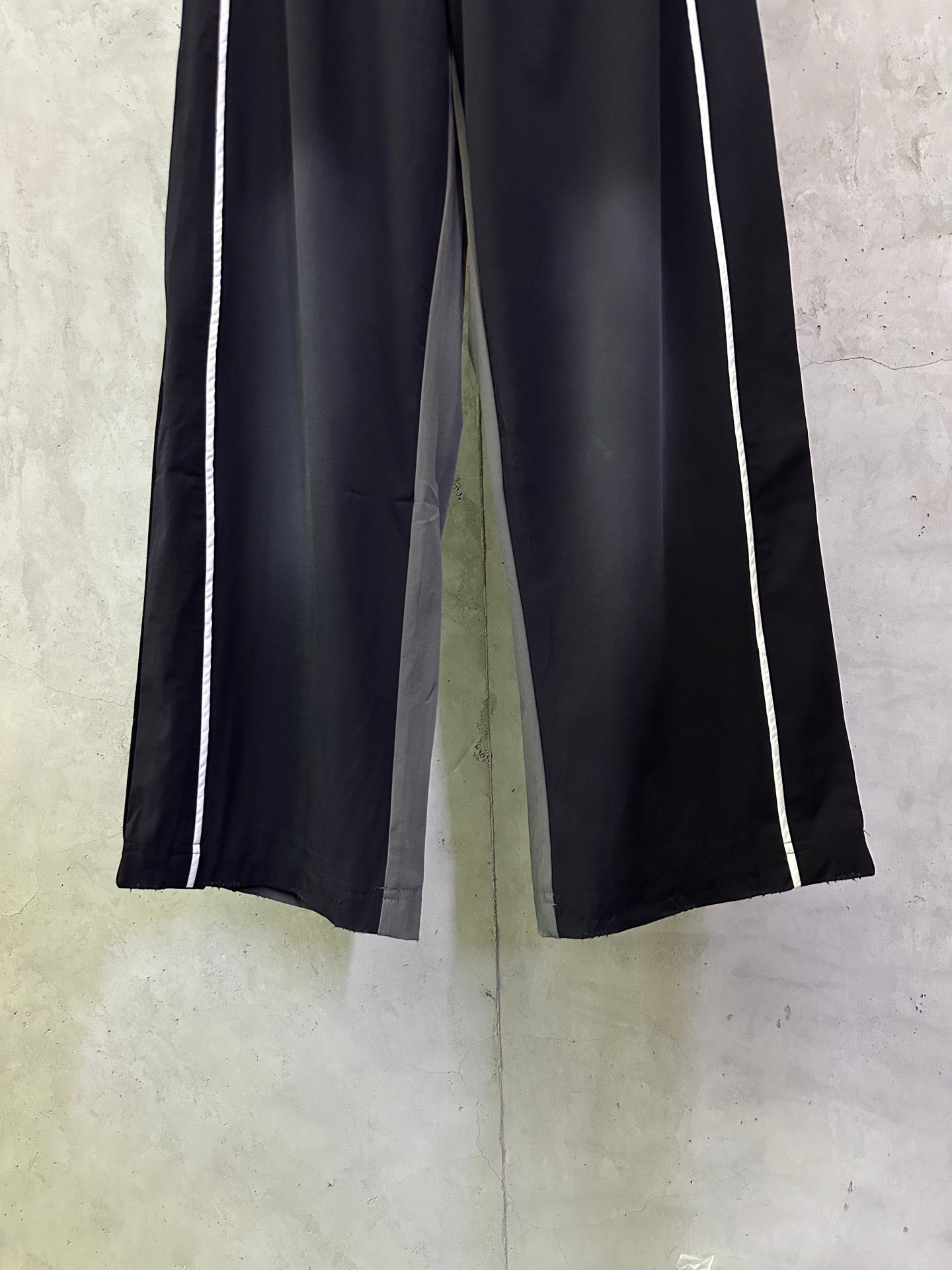 Dark navy wide-leg track pants with white side stripes and elastic waistband