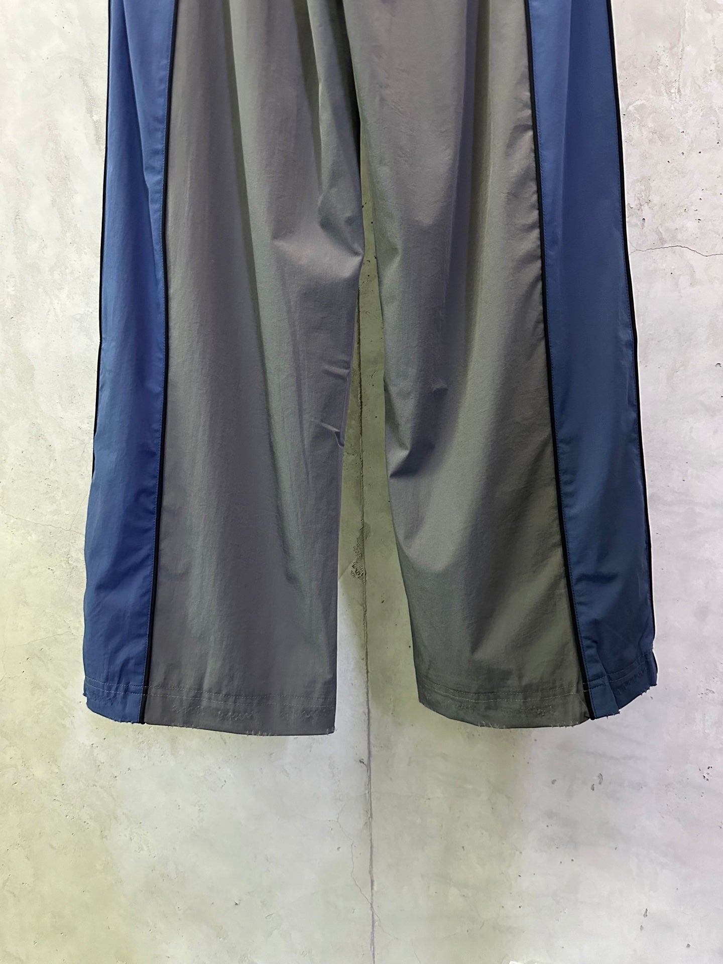 Two-tone track pants with blue outer panels and gray draped legs