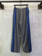 Two-tone track pants with gray center and blue side panels, elastic waistband