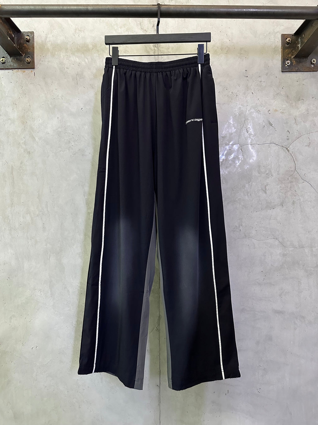 Balenciaga navy track pants with white side stripes and elastic waistband