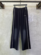 Balenciaga navy track pants with white side stripes and elastic waistband