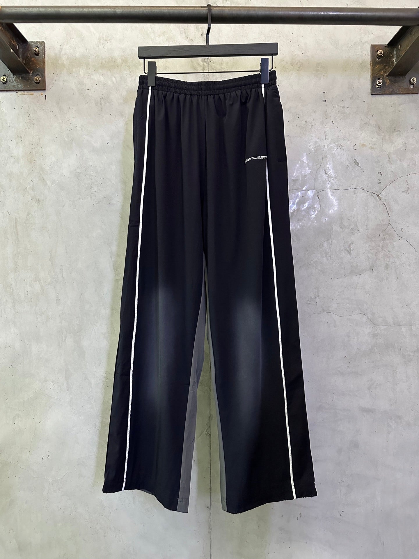 Balenciaga navy track pants with white side stripes and elastic waistband