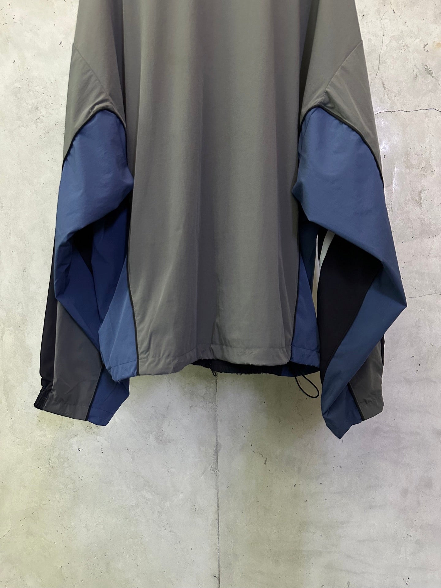 Balenciaga zip jacket back view, dark gray with blue panel cuffs and draped sleeves